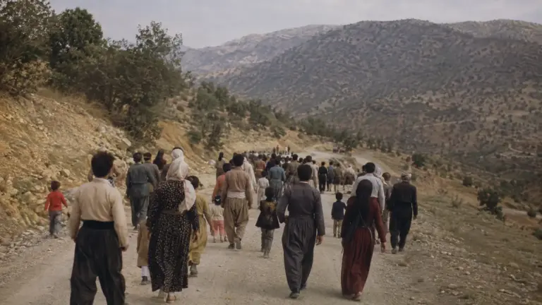 گروهی از مردم در حال حرکت در جاده‌ای کوهستانی در کردستان